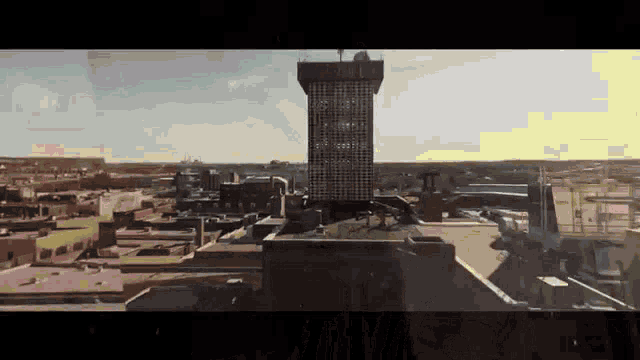 an aerial view of a city with a tall building in the foreground and a smaller building in the background