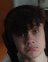 a close up of a young man wearing headphones making a funny face .