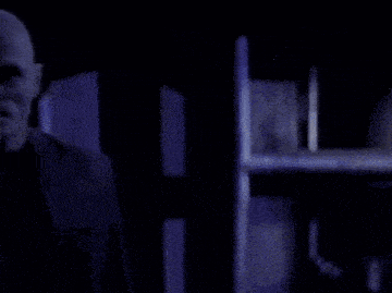 a man with his face covered in liquid is standing in the dark in a room .