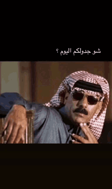 a man wearing sunglasses and a head scarf with arabic writing