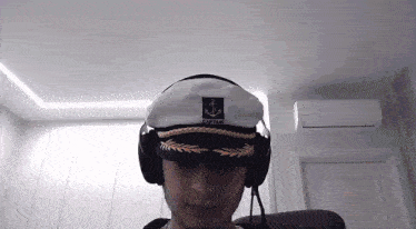 a man wearing a captain hat and headphones looks at the camera