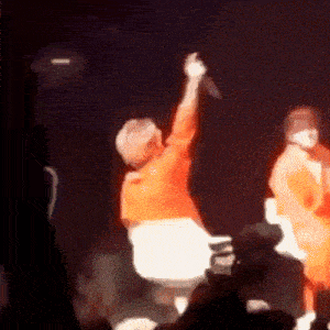 a man in an orange shirt is holding up a microphone in the air