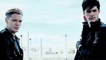 two men are standing next to each other in front of a city .