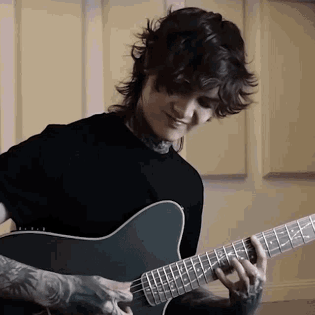 a man in a black shirt plays a guitar