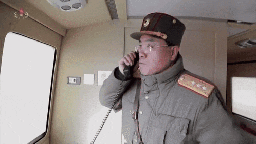a man in military uniform is talking on a phone