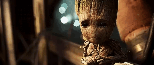 a baby groot from guardians of the galaxy is crying and holding a book .