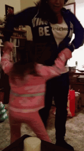 a woman wearing a shirt that says " the be " holds a little girl