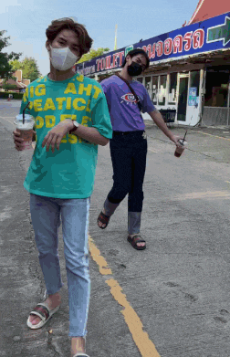 two men wearing face masks are walking down a street in front of a sign that says toilet