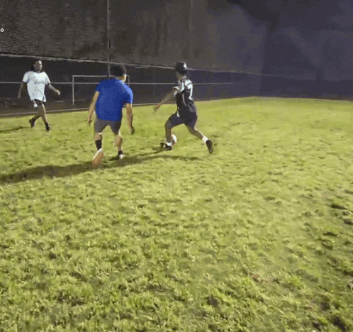 a man in a blue shirt is playing soccer with another man