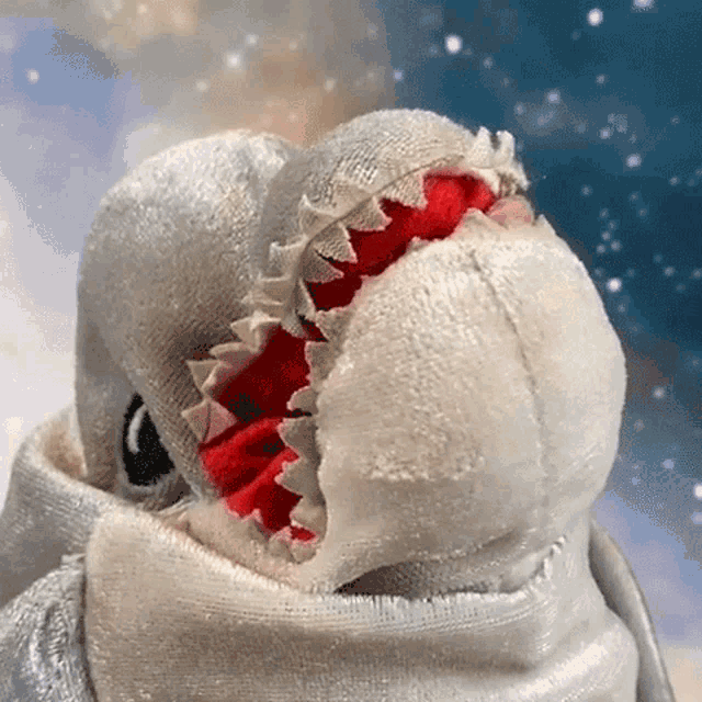 a close up of a stuffed animal with a red mouth and teeth