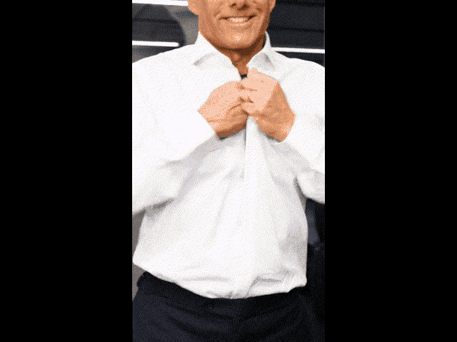 a man is taking off his shirt and smiling while wearing a white shirt