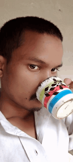 a man with a mustache is drinking from a colorful mug