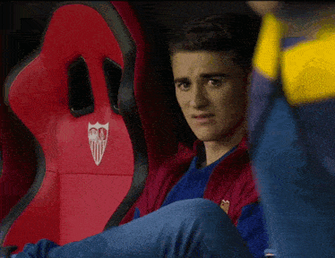 a man sits in a red chair with a logo on it that says sevilla