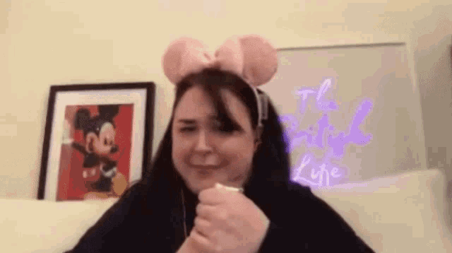 a woman is wearing a headband with mickey mouse ears and a bow .