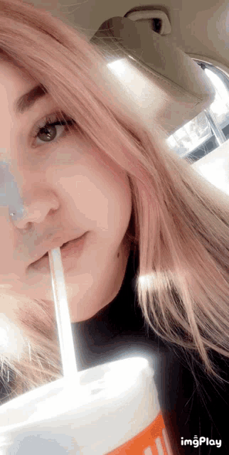 a girl with pink hair drinking through a straw from a cup that says imgplay on it