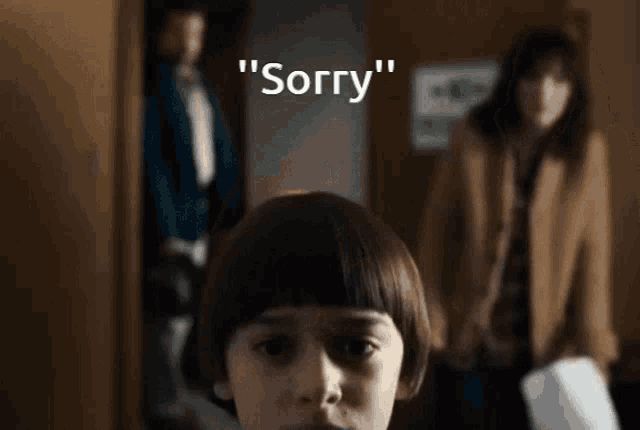 a young boy is standing in front of a sign that says " sorry " on it