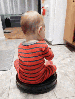 a baby is sitting on a vacuum cleaner on a tiled floor