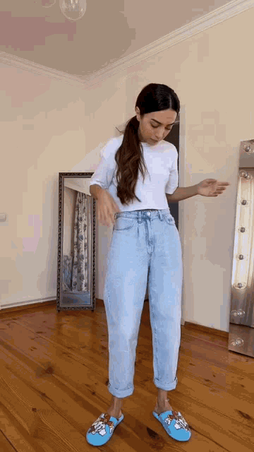 a woman is standing in front of a mirror wearing a white shirt and blue slippers
