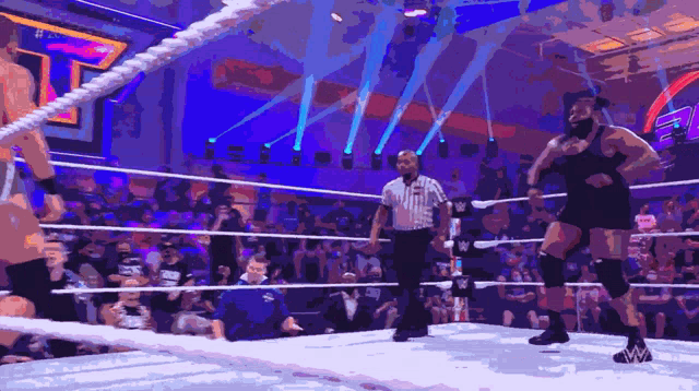 a referee stands in the middle of a wrestling ring with two wrestlers
