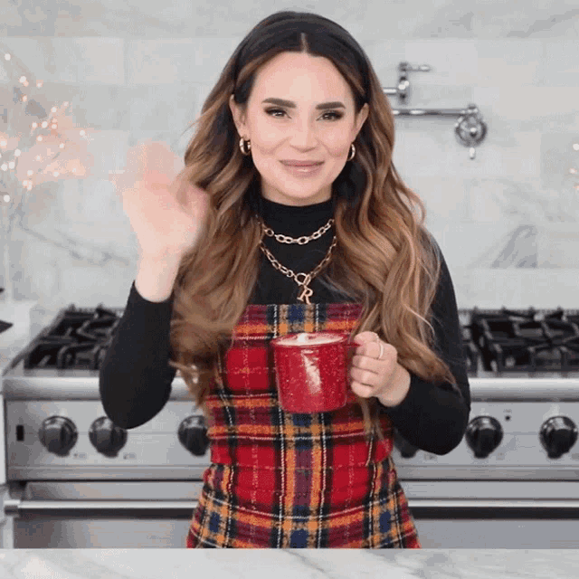 a woman in a plaid dress is holding a red cup with the letter r on it