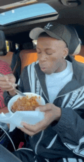 a man is sitting in a car eating a bowl of food