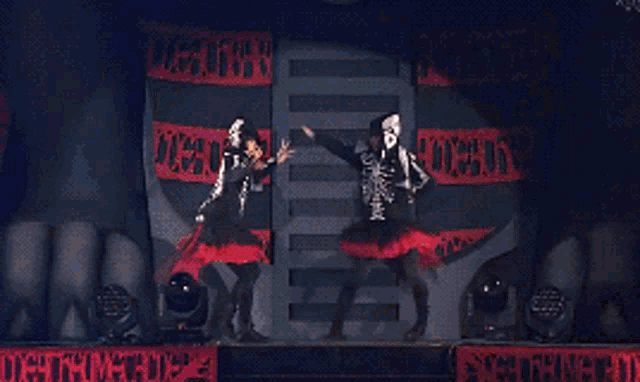 two girls in skeleton costumes are dancing in front of a sign that says " justice "