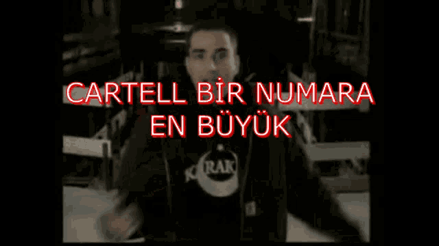 a man in a black jacket is pointing at the camera with the words " cartell bir numara en buyuk " below him