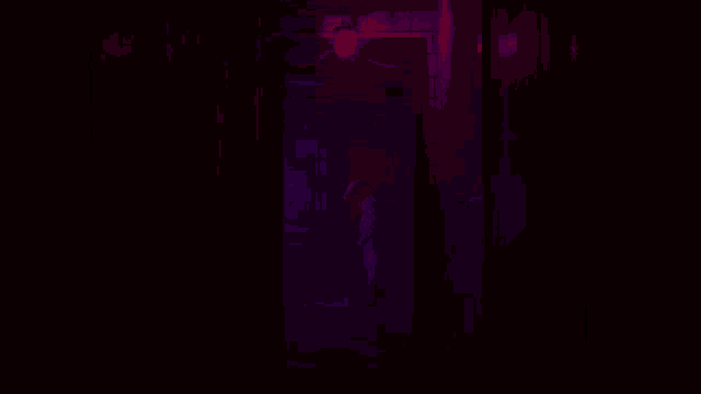 a person is sitting in a dark room with a purple light behind them holding a can of diet coke .