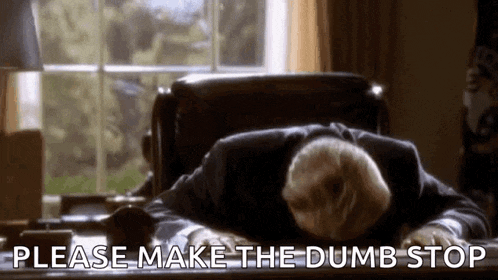 a man in a suit is laying on a desk with his head on his desk .