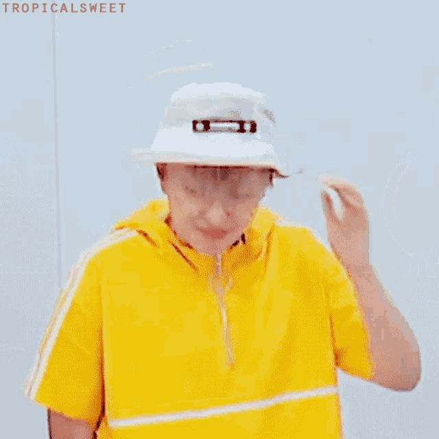 a young man wearing a yellow shirt and a white hat .