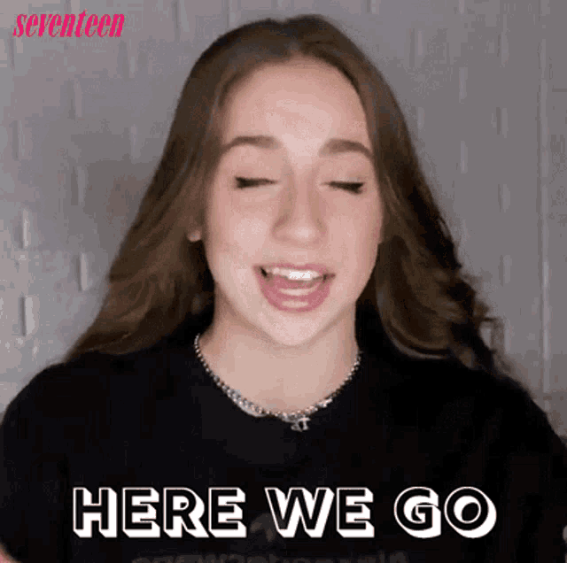 a girl wearing a black shirt with the words here we go on it