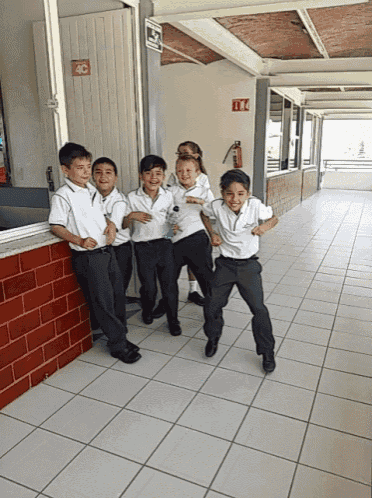 a group of young boys are standing in a hallway with a fire extinguisher in the corner