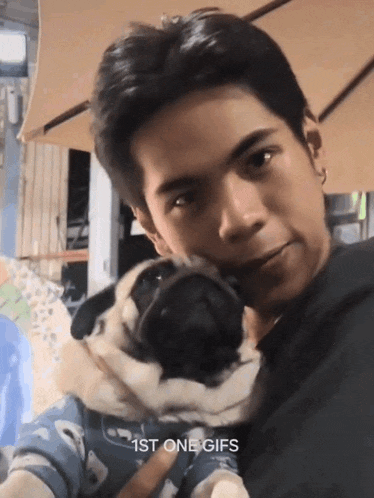 a man holds a pug dog in his arms with the caption " 1st one gifs "