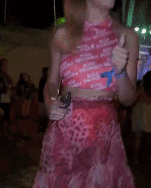 a woman in a pink crop top and a red skirt is dancing