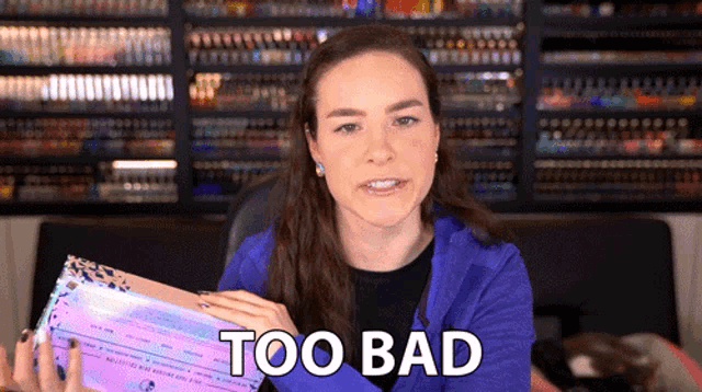 a woman in a blue jacket is holding a box that says too bad on it