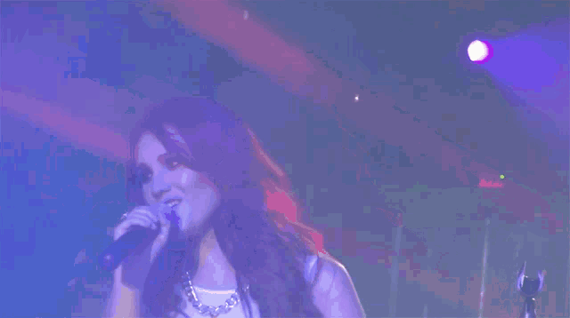a woman singing into a microphone in front of a blue background