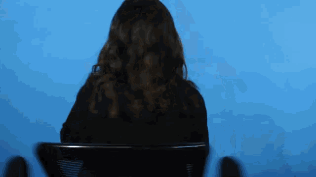 a woman sitting in a chair with her back to the camera