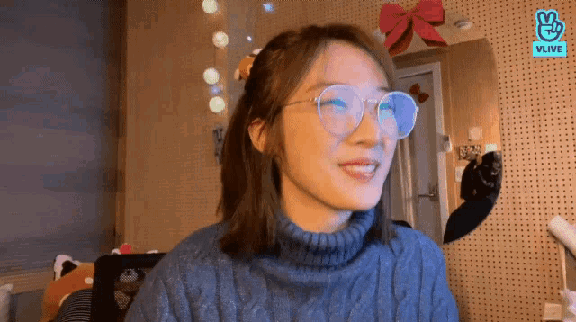 a woman wearing glasses and a turtleneck sweater is smiling .