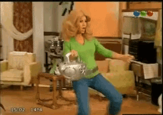 a woman in a green shirt is dancing in a living room with the time 15:04