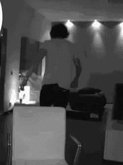 a man in a white shirt is standing in a living room .