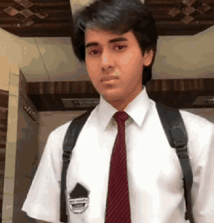 a man wearing a white shirt and a red tie has a badge on his pocket