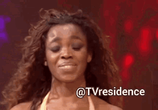 a woman with curly hair is smiling in front of a sign that says tvresidence