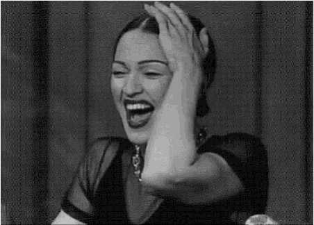 a woman is laughing and covering her face with her hands .
