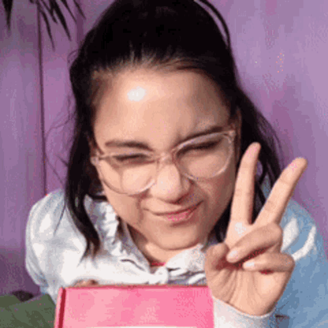 a woman wearing glasses is making a peace sign