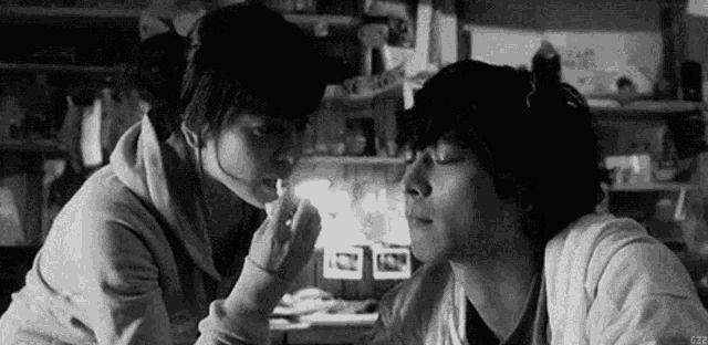 a black and white photo of a man and a woman kissing .