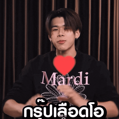 a man wearing a mardi shirt is holding a red heart