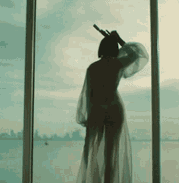 a woman standing in front of a window with a sword in her hair