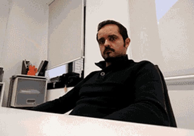 a man with a mustache sits at a desk