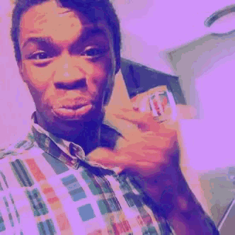 a man in a plaid shirt is making a funny face while holding something in his hand