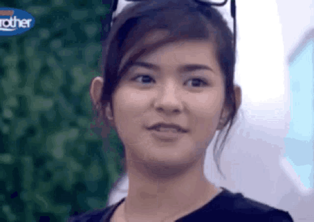 a close up of a woman 's face with a blurry background and a blue sign that says brother .